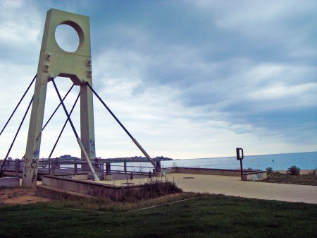 Pont dels ànecs al passeig de Sant Antoni de Calonge amb el mar al fons. La lluna sortirà pel costat dret del port 